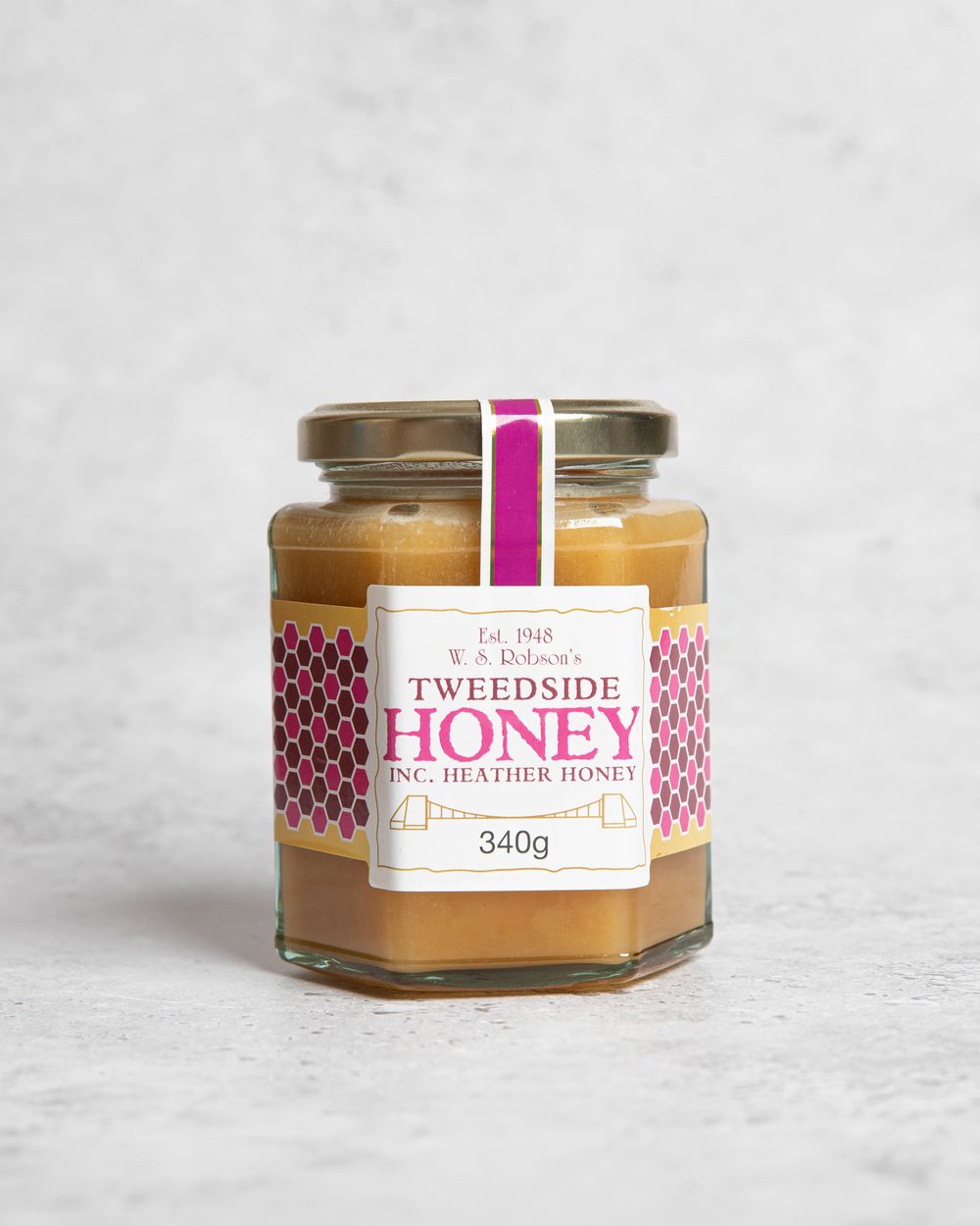 A hexagonal jar of golden honey including heather honey
