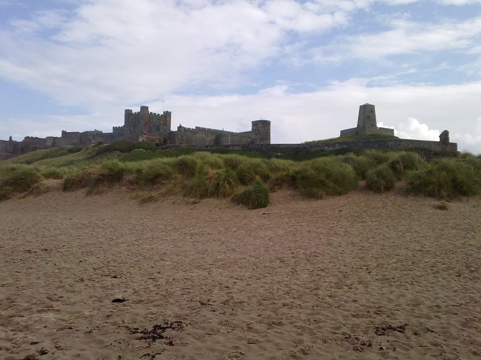 Bamburgh Castle rising above the marram grass and golden sand of Bamburgh Beach