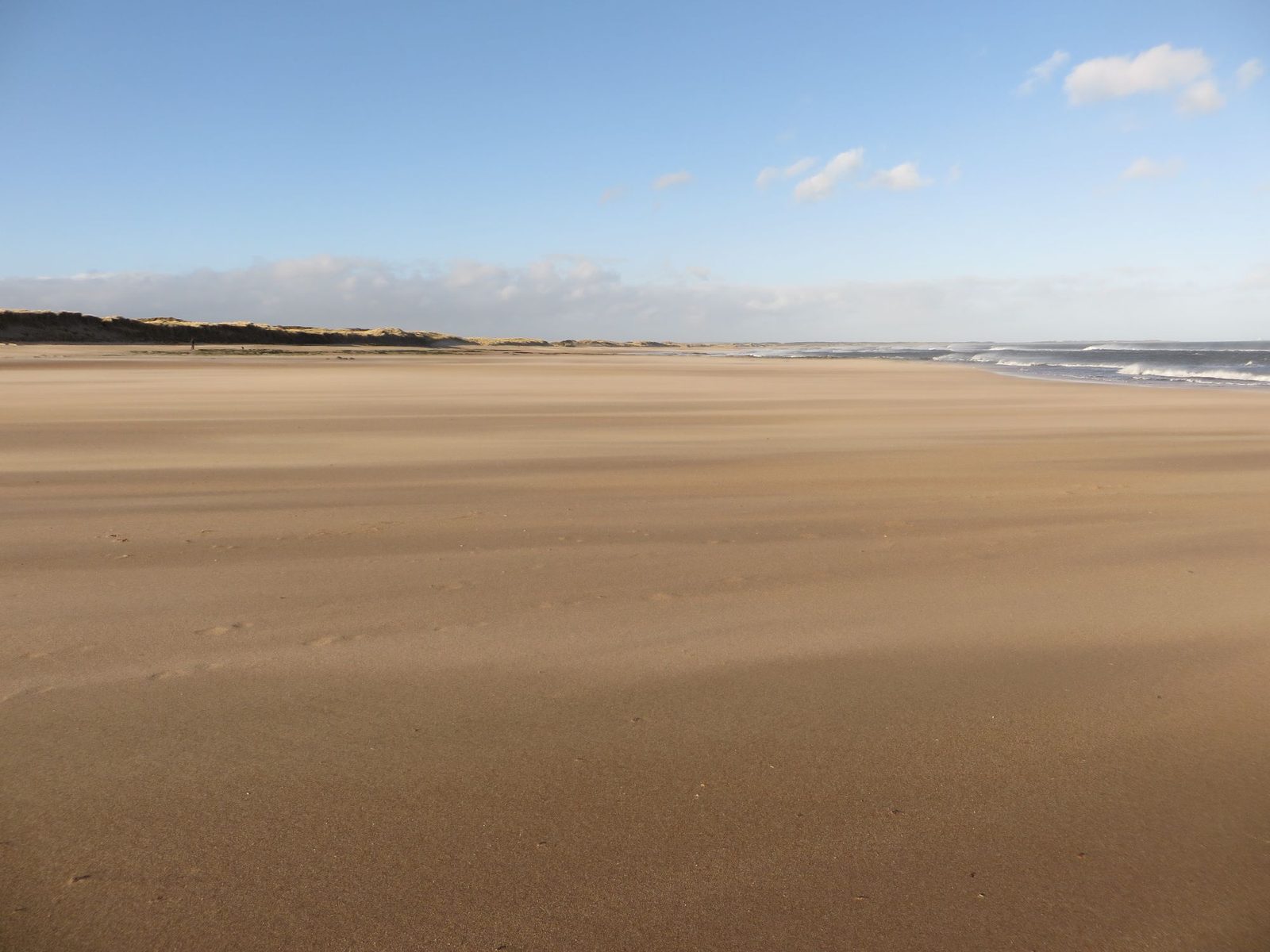 The huge open expanse of firm sand and distant dunes at Druridge Bay