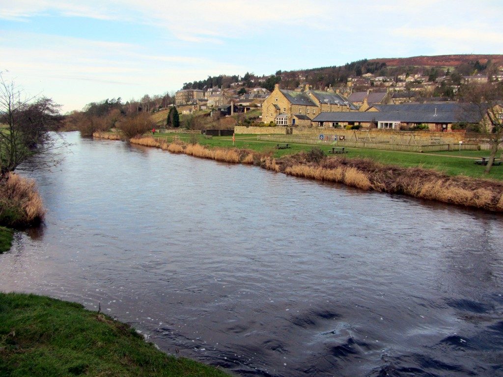 The River Coquet running past the stone houses and riverside green at Rothbury