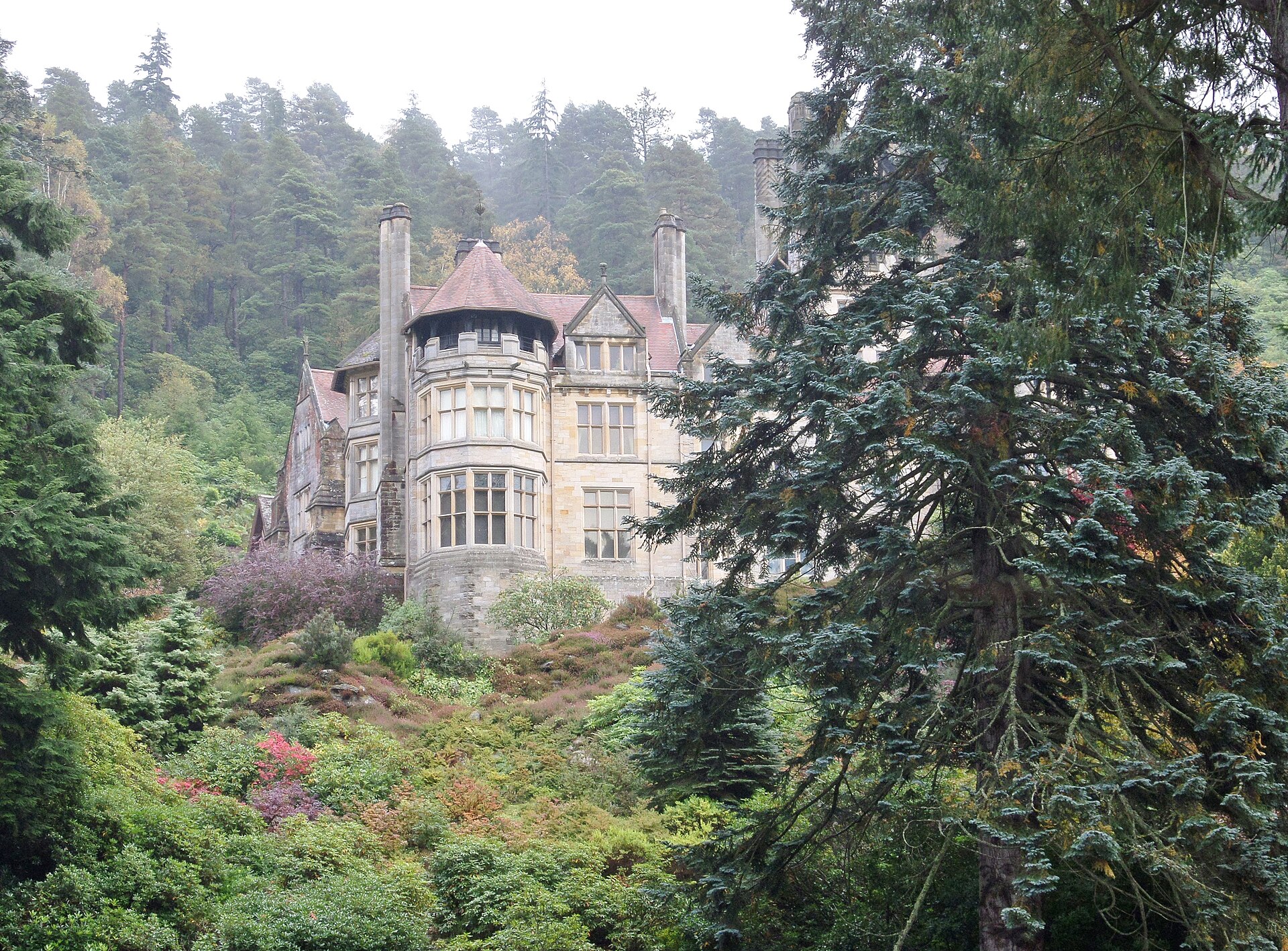 Cragside House at Rothbury surrounded by tall conifers and the flowering rockery
