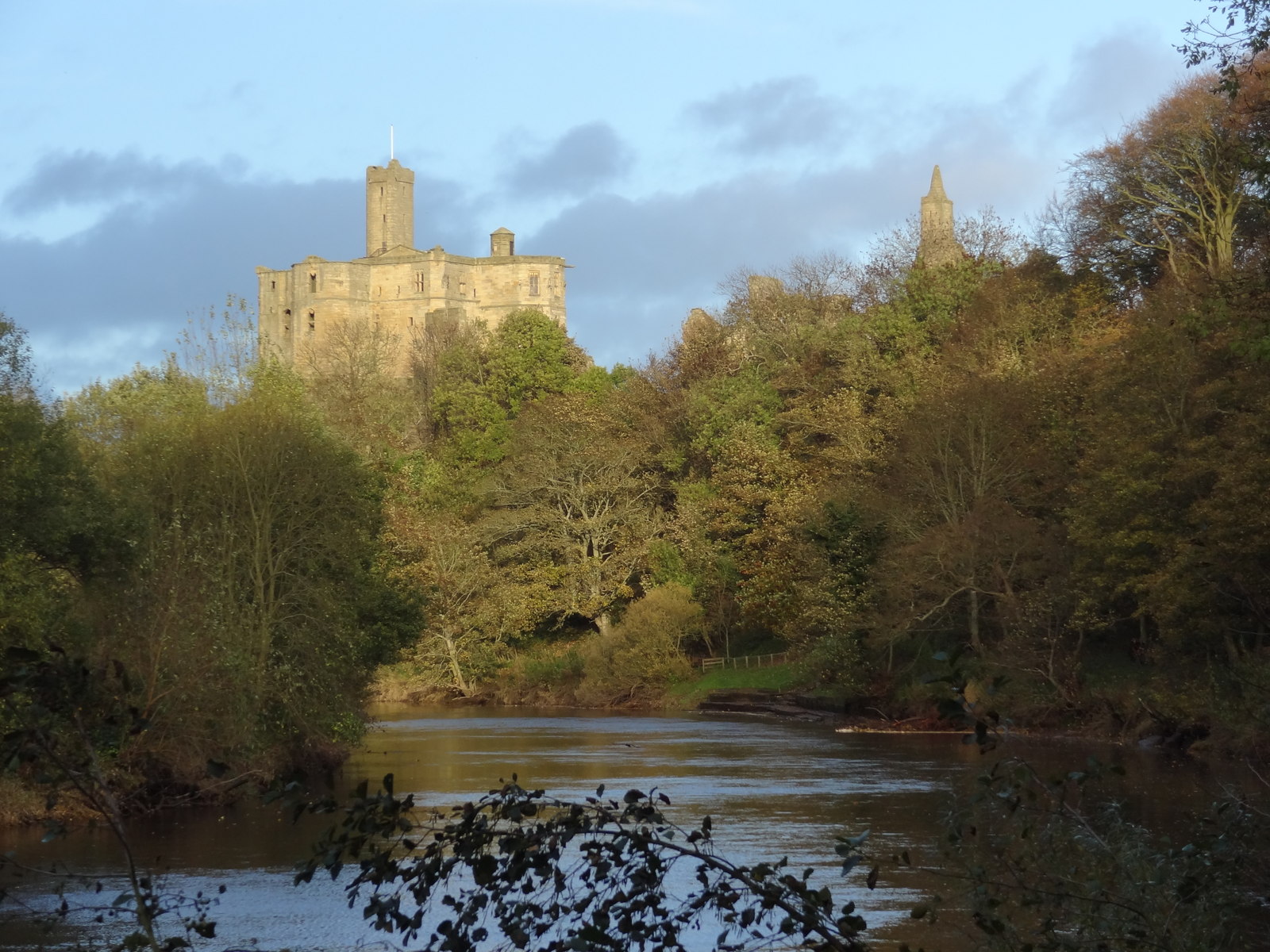 Warkworth Castle rising above the trees and the River Coquet in Northumberland